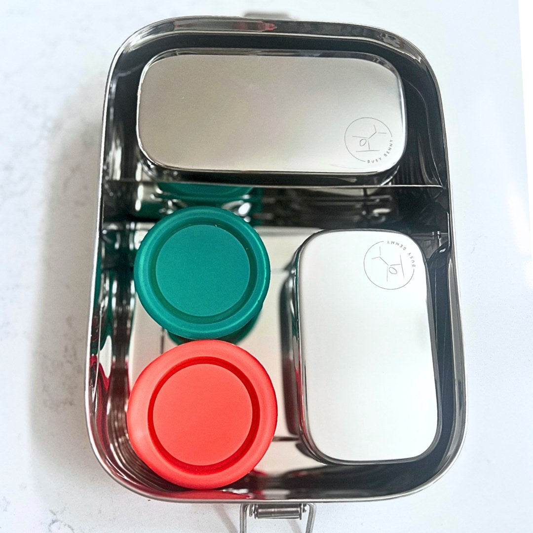 Metal lunch box with colorful lids on a white background