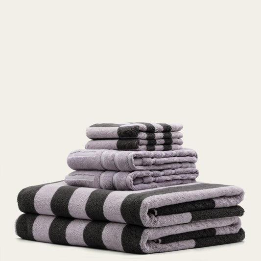 Stack of folded gray and black striped towels on a light beige background