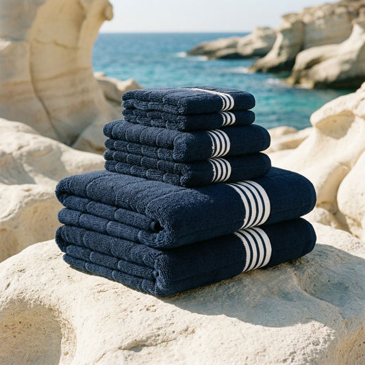 Stack of navy blue towels with white stripes on a rocky beach.